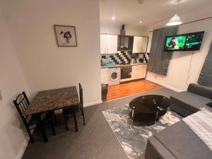 a living room with a table and a couch and a kitchen at Stratford London Apartment in London