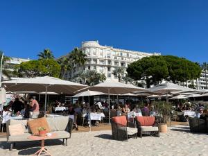 un groupe de tables et de chaises avec parasols devant un bâtiment dans l'établissement Croisette Palais Miramar - sea view, à Cannes