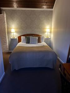 a bedroom with a large bed with two lamps at The Bulls Head, Clipston in Clipston