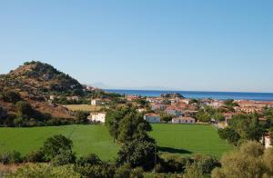 a village with a green field and the ocean at Guesthouse Karidia in Skala Eresou