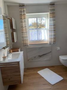 ein Bad mit einem Waschbecken, einem WC und einem Fenster in der Unterkunft Außergewöhnliche Ferienwohnung in modernen Styl in Weiding