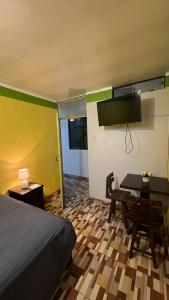 - une chambre avec un lit, un bureau et une télévision dans l'établissement Waylla Hostel, à Huaraz
