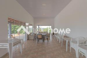 a dining room with white tables and chairs at Casa em Paranapanema com piscina e área de lazer. in Itaí