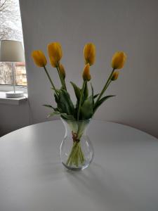 a vase of yellow flowers sitting on a table at Magnolia in Toruń