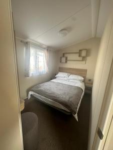 Habitación pequeña con cama y ventana en 4 Bed 10 Berth Caravan Seawick Holiday Park, en Saint Osyth
