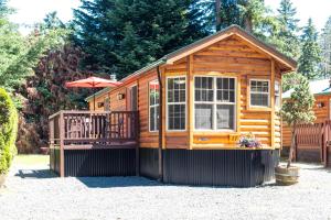 Cabaña de madera con balcón y sombrilla en Riverbend Cottage & RV Resort, en Parksville
