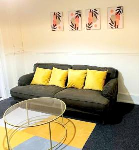 a black couch with yellow pillows and a glass table at Gravesend 1 bedroom Apartment in Gravesend