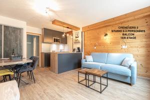 een woonkamer met een blauwe bank en een keuken bij LES CHENEVERS in Lanslevillard