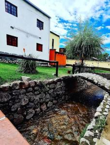 eine Steinbrücke über einen Bach vor einem Gebäude in der Unterkunft Hostal La Vidala in Tafí del Valle