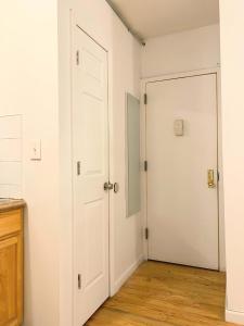 Dos puertas blancas en una habitación con pisos de madera. en Shered bathroom 4 SofaBed + loftbed + kitchen, en Nueva York