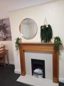 a fireplace with a mirror on a white wall at A Cosy Private Space- Free Wifi & Parking in Leeds