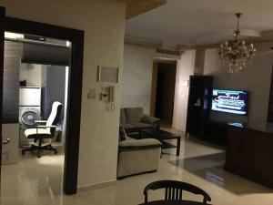 a living room with a couch and a tv at SAK Suites in Rujm ash Sharāʼirah