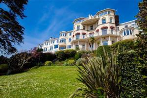 a large white building on top of a lush green yard at 180° Water View Apartment - Simply Amazing in Torquay