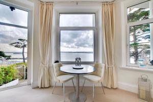 comedor con mesa, sillas y ventanas grandes en 180° Water View Apartment - Simply Amazing, en Torquay