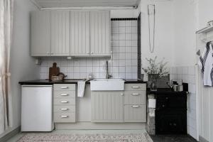 a kitchen with white cabinets and a white sink at Lillebo - Centralt mysigt hus i Nora in Nora