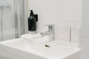 a bathroom sink with a faucet and a bottle of soap at Stylish APT for 4-6 metro & walk 5 min to center in Vienna