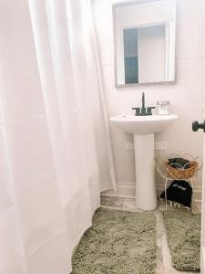 bagno bianco con lavandino e specchio di Hub Cottage a Hattiesburg