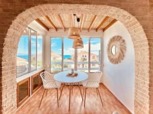 a dining room with a table and chairs and windows at Casa Natura Carabassi Beach in Gran Alacant