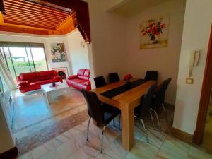 sala de estar con mesa y sofá rojo en Appartements de charme à la palmeraie en Marrakech