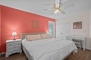 a bedroom with a white bed and a red wall at Golden Hour on Greenville- 1.5 blocks to beach, Pet Friendly, & No Hidden Fees!! in Carolina Beach