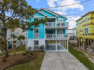 a blue and white house with a balcony at Golden Hour on Greenville- 1.5 blocks to beach, Pet Friendly, & No Hidden Fees!! in Carolina Beach