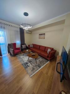 a living room with a red couch and a tv at Anoe City Center Apartment in Shkodër