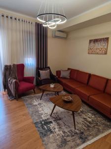 sala de estar con sofá rojo y mesa en Anoe City Center Apartment, en Shkodër