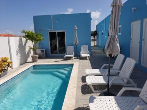 a swimming pool with chairs and an umbrella at Apricity Suites Aruba in Noord