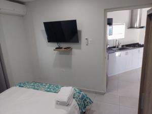 Cette chambre blanche dispose d'une télévision murale. dans l'établissement Apricity Suites Aruba, à Noord