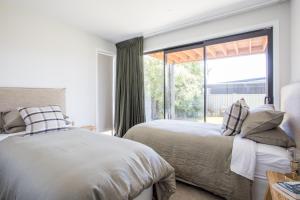 Dos camas en un dormitorio con una gran ventana. en Super Central in Wanaka, en Wanaka