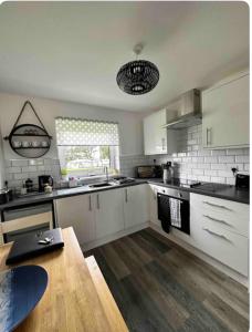 uma cozinha com armários brancos e uma mesa de madeira em 44 Gower holiday village Ty Gŵyr Cosy 2 bedroom Chalet em Swansea