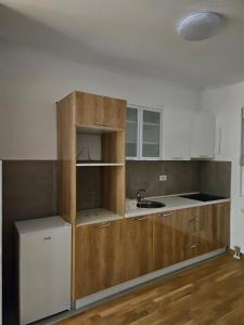 uma cozinha com armários de madeira e um lavatório em BELIV apartman em Stari Banovci