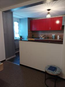 a kitchen with red cabinets and a counter with a stool at Au doux refuge in Zimmersheim