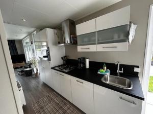 eine Küche mit weißen Schränken und einer schwarzen Arbeitsplatte in der Unterkunft Ferienhaus / Chalet / Bungalow am See, Holland, Niederlande, Lathum in Lathum