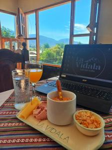 un ordenador portátil sentado en una mesa con un plato de comida en Hostal La Vidala en Tafí del Valle