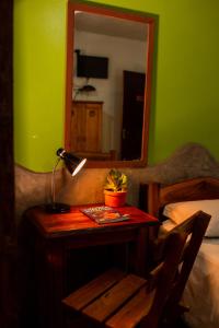 a bedroom with a table with a lamp and a mirror at Pousada Tatu Feliz in Vale do Capao