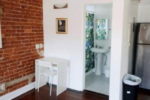 baño con pared de ladrillo y lavabo blanco en Melrose Gem: Stylish Living near Iconic Landmarks, en Los Ángeles