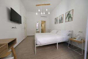 a white bedroom with a bed and a flat screen tv at Roman Forum Holiday Termini in Rome
