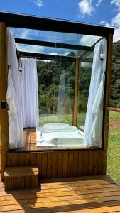 uma grande janela com uma banheira num deque em Domo da Montanha em Monte Verde