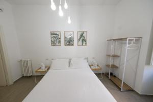 a white bedroom with a large bed and three pictures on the wall at Roman Forum Holiday Termini in Rome