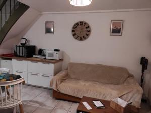 ein Wohnzimmer mit einem Sofa und einer Uhr an der Wand in der Unterkunft la maison du bonheur in Alençon