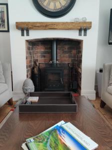 a living room with a fireplace with a clock on the wall at Rose Cottage, Newbiggin-by-the-Sea in Woodhorn