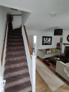 a staircase in a living room with a couch at Rose Cottage, Newbiggin-by-the-Sea in Woodhorn