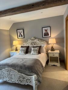 The Coach House في Chedworth: غرفة نوم بسرير ابيض كبير مع طاولتين