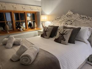 a bedroom with a large white bed with pillows at The Coach House in Chedworth