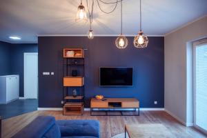a living room with a blue wall with a tv at Apartament Słoneczny in Kwidzyn