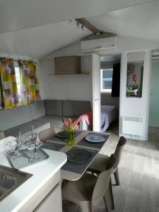 uma cozinha e sala de estar com mesa e cadeiras em Mobil-home Siblu Les Rives de Condrieu em Condrieu