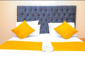un lit avec des oreillers jaunes et une tête de lit bleue dans l'établissement Nuri Homes, à Kisii