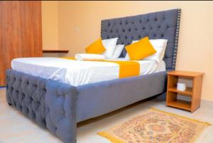Elle comprend un grand lit avec des oreillers jaunes et blancs. dans l'établissement Nuri Homes, à Kisii