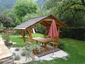 a wooden gazebo with a table and an umbrella at Haus Binderschuster in Unken